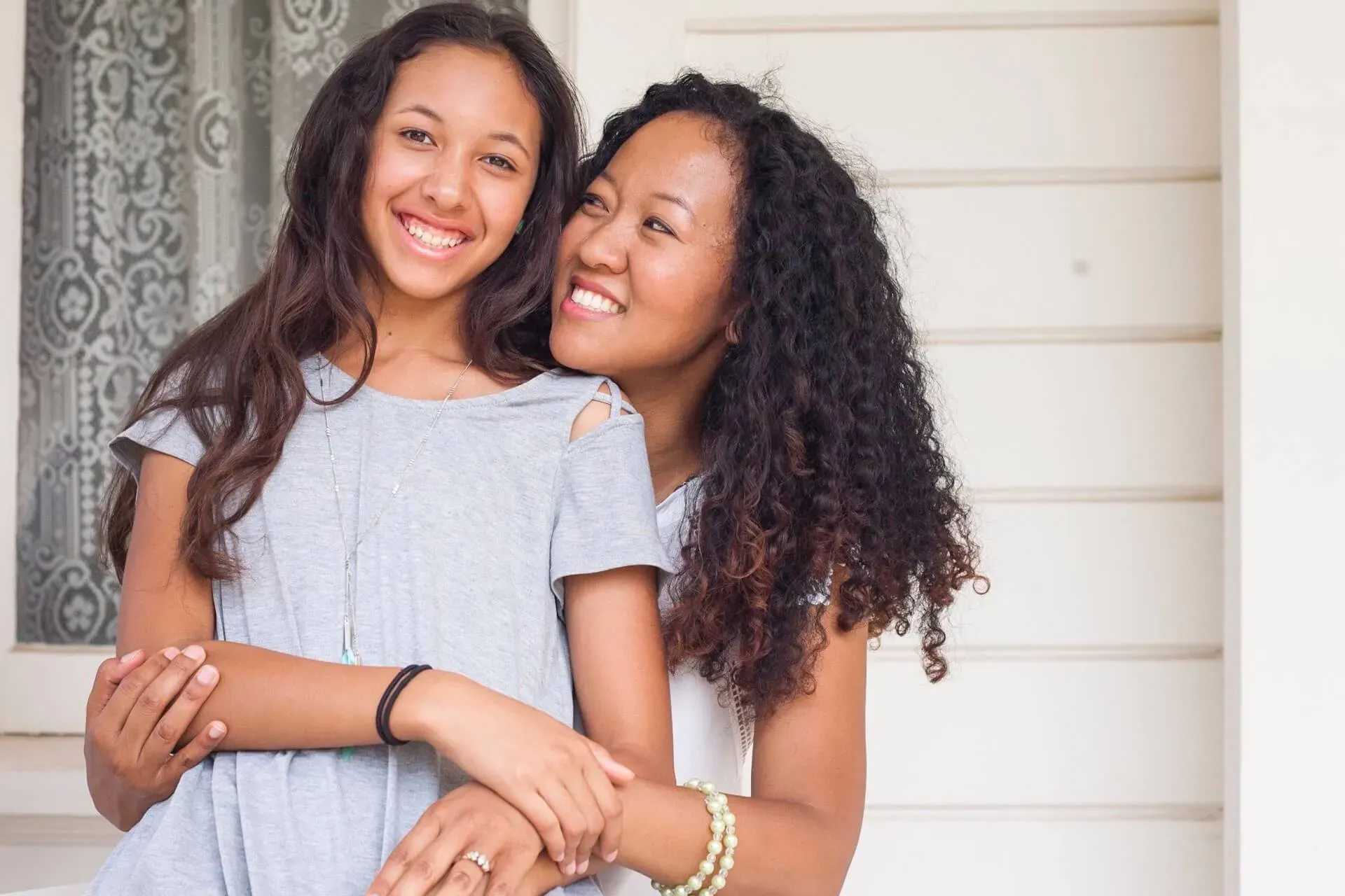 A smiling teen and her mother hugging